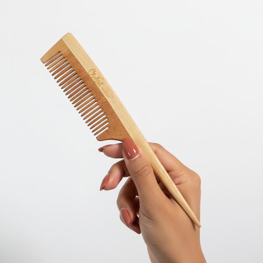 Hand holding a wooden comb against a light gray background