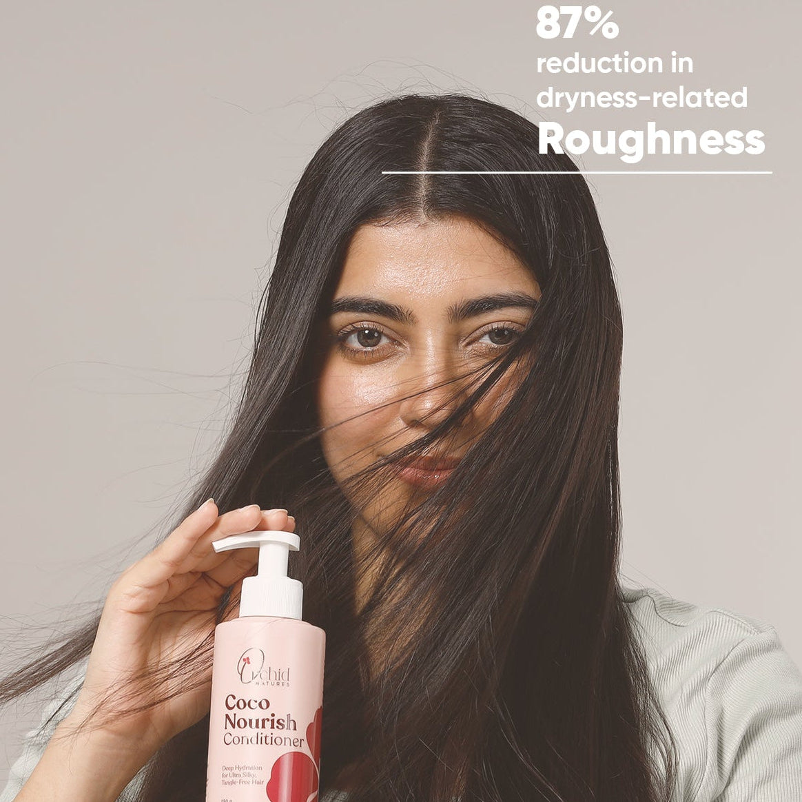 Woman holding a bottle of hair care product with text on a plain background