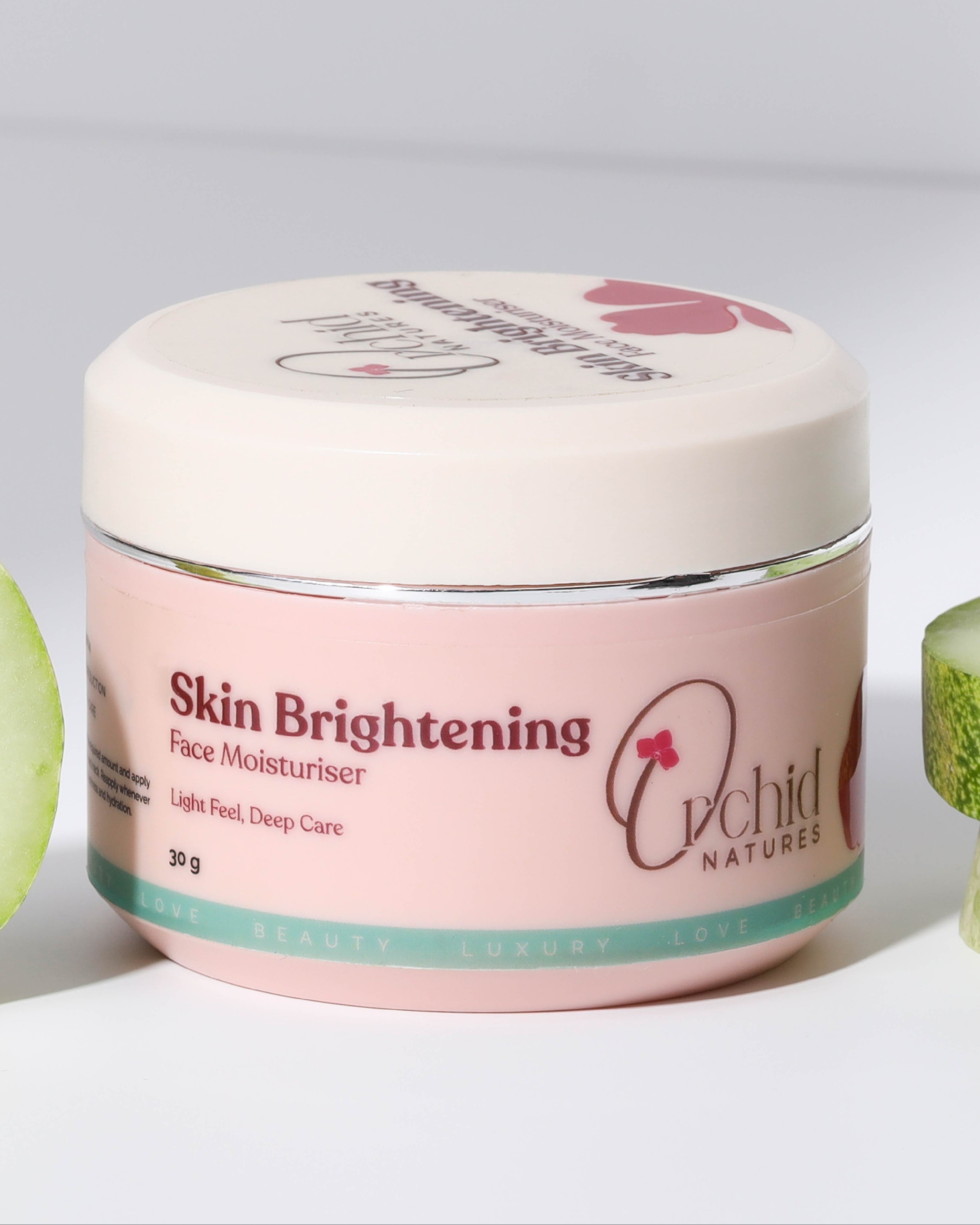 Jar of 'Skin Brightening Face Moisturizer' with cucumbers on a light gray background