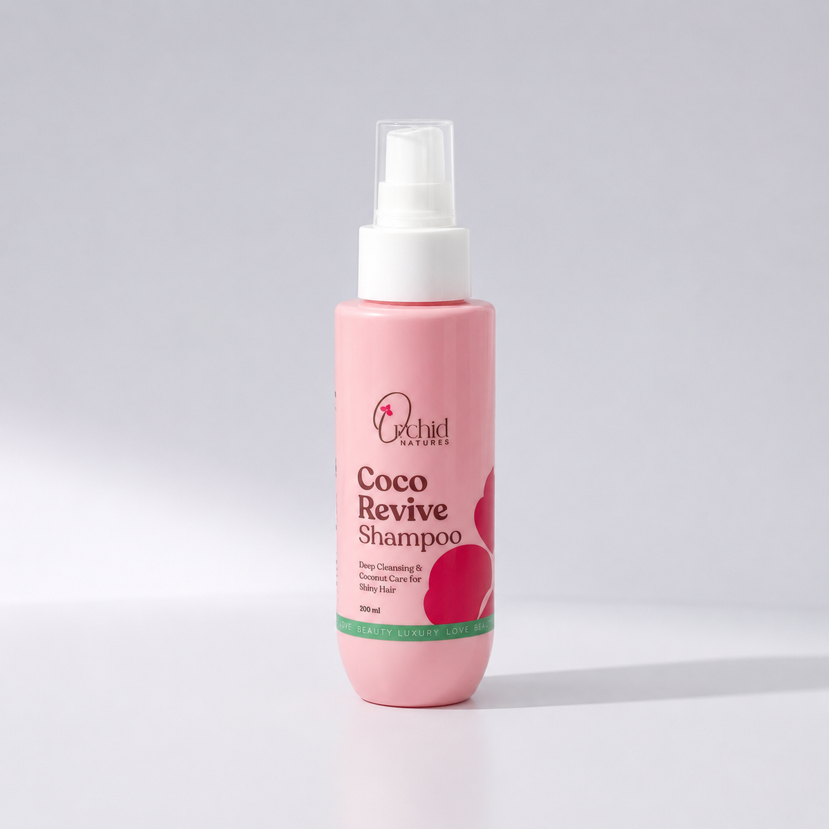 Pink bottle of Orchid Naturals Coco Revive Shampoo on a light gray background